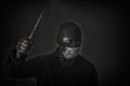 Bandit in black mask with a slit for the eyes and a medical mask waving a knife. Low hatch. Royalty Free Stock Photo