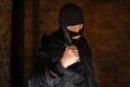 A bandit in a black mask threatens with a knife in a room of an empty dark building Royalty Free Stock Photo