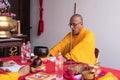 A Bald Monk praying while wearing an orange suit at the temple