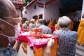 An Older man wearing a white mask while holding a tray and praying in pandemic