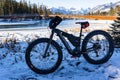 A fat tire bike parked in the snow overlooking a pedestrian bridge and Canadian Rocky