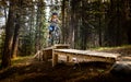 A female cyclist rides her mountain bike down a wooden ramp on the Top Notch cycling trail on
