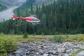 Banff, Canada - 08.30.2018: Red and blue Alpine helicopter going to touch down in a green meadow in Canadian Rockies. Service for