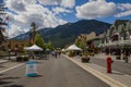 Banff downtown life - cars parked near houses, cafes, people walking on the streets. Summer day in a mountain village.