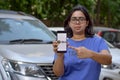 Bangalore, India, 2020. Girl showing Ola app on her mobile phone screen while standing in front of her fleet of cars. Its an
