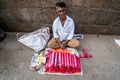 An Indian street vendor selling incense sticks on a pavement sidewalk on the streets