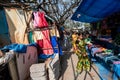 An Indian woman holding a child walking on a pavement crammed with shops and stalls in