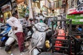 A textile store in a busy chaotic crowded market with parked vehicles and people in