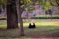 Two young Indian women sitting under a tree on the greed grass of the Lalbagh