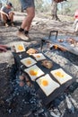 Bacon and eggs or toad in a hole being cooked on the open camp fire