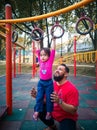 Child on monkey bars with father. Little girl hanging on gym play ground. Healthy outdoor Royalty Free Stock Photo