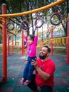 Child on monkey bars with father. Little girl hanging on gym play ground. Healthy outdoor Royalty Free Stock Photo