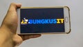 Hand holding a smartphone with the BUNGKUSIT application logo on the screen