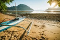 Bangka boat on sandy beach with golden sunset light over tropical islands in background. El Nido bay. Philippines Royalty Free Stock Photo