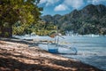 Bangka fishing boat on shore with El Nido village in background, Palawan, Philippines Royalty Free Stock Photo