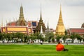Bangkok, Bhuddist monk sitting in Sanam Luang park with Wat Phra Kaeo
