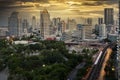 Bangkok business district with the public park area anf the sky train in the foreground at sunset time