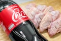 BANGKOK, THAILAND - APRIL 04, 2019: Bottle of Coca-Cola next to raw chicken wings on a cutting board in the kitchen