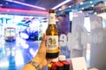 BANGKOK, THAILAND - APRIL 14 , 2018: handed bottle of cold singha beer on blurred colorful light bokeh at reatautant, selective