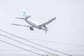 Plane of Cathy Pacific Airlines or Airways on the sky landing to Suvanabhumi airport. with blurry electric wires cable.