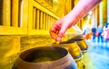 Dropping coin in bronze bowl in Wat Pho temple, Bangkok, Thailand