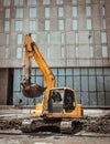 A construction excavator of yellow color is parked in front of the building construction site Royalty Free Stock Photo