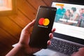 Bangkok, Thailand - August 6, 2019: Hands holding Smartphone with Mastercard logo screen and Mastercard website. Mastercard Is