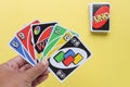 Bangkok, Thailand : August 13, 2023 : Uno game cards in the player\'s hand on light yellow background.