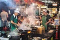 Bangkok, Thailand: a chef cooks in a wok on the open flame of the stove with rising steam and smoke at a street cafe in Chinatown