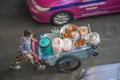 boy at a portable snack car offers fresh grilled chicken sticks on the street in Bangkok