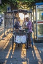 woman at a portable snack car offers fresh grilled chicken sticks on the street in Bangkok