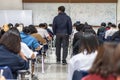 School exam room with teacher invigilator monitoring students taking educational examination in classroom for admission test Royalty Free Stock Photo