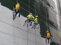 Suspended on ropes, workers paint a facade