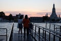 Two young girls stand on the river bank and admire the temple of Wat Arun at sunset. Berth Royalty Free Stock Photo