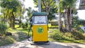 Yellow and green vintage gasoline or gas station on footpath with pathway and garden background. Royalty Free Stock Photo