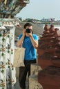 European tourist holding camera by his eyes. Portrait of a guy shooting a camera man.