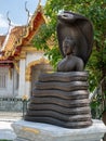 Bangkok, Thailand - February 04, 2023: Bronze buddha statue entwined with cobra