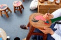 Asian female hands painting picture on tamarind wooden chair in Thai art and culture exhibition