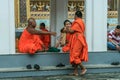 Group of Buddhist monks as tourists resting in the shadows on the territory of Grand Palace.