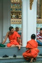 Group of Buddhist monks as tourists resting in the shadows on the territory of Grand Palace.