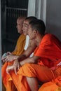 Group of Buddhist monks as tourists resting in the shadows on the territory of Grand Palace.