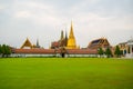 Bangkok, Thailand - January 25, 2016: Green grass outside the Grand Palace in Bangkok with stupas and temple roofs behind Royalty Free Stock Photo