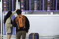 Bangkok, Thailand - January 17, 2023 :  young asian man and woman passengers with luggage looking at departure timetable board to Royalty Free Stock Photo