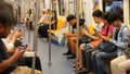 BANGKOK, THAILAND - 13 JULY, 2019: Asian passengers in train using smartphones. Thai people online surfing internet in bts car. Royalty Free Stock Photo