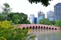 Bangkok,Thailand - July 27,2023 : A beautiful red bridge in Jatujak public park with a high building around the area Royalty Free Stock Photo