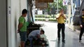 BANGKOK, THAILAND - 11 JULY, 2019: Ethnic cobbler working on city street. Side view of ethnic man sitting on chair near client and