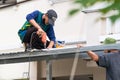 Bangkok, Thailand- July,19, 2022 : Two Asian workers, roofing crews installing bolt on the house roof top at Bangkok, Thailand