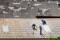 Three handyman workers repairing tiles on the damaged factory roof