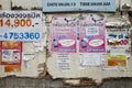 Bangkok, Thailand - June 29, 2015: Messy and dirty advertisement papers on old wooden wall in Bangkok street