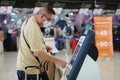 Bangkok, Thailand - June 30, 2023 : senior asian chinese man tourist visitor with protective face mask are self service check in